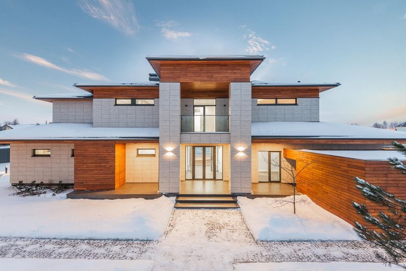 A contemporary house in stone and timber with wide glazing.