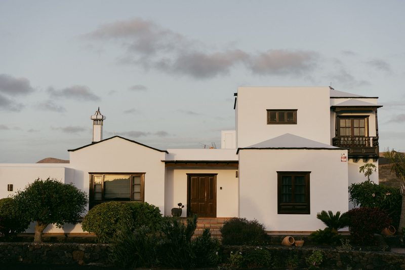 A white modern villa with a walled garden.