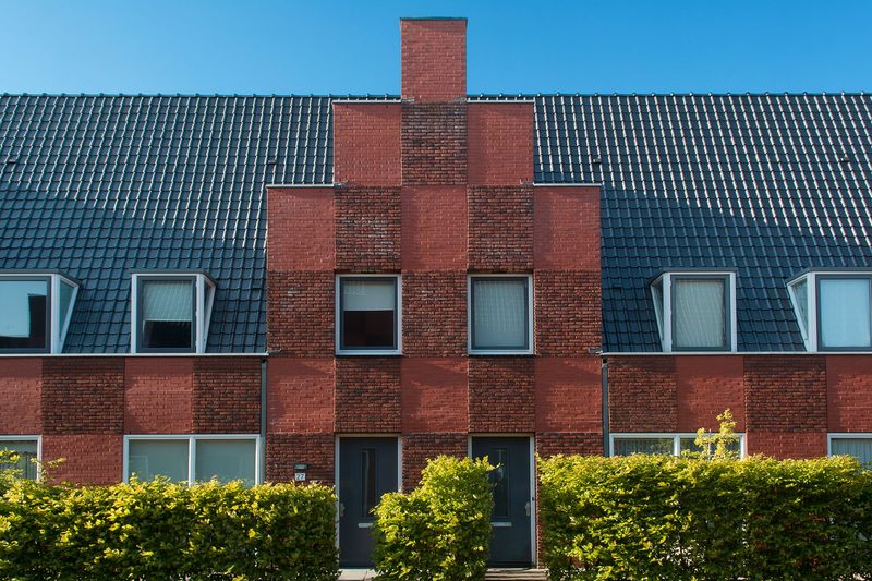 A terrace of brick townhouses behind a clipped hedge.