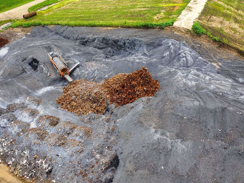 Aerial photograph showcasing a pile of waste material on black soil in an open field.