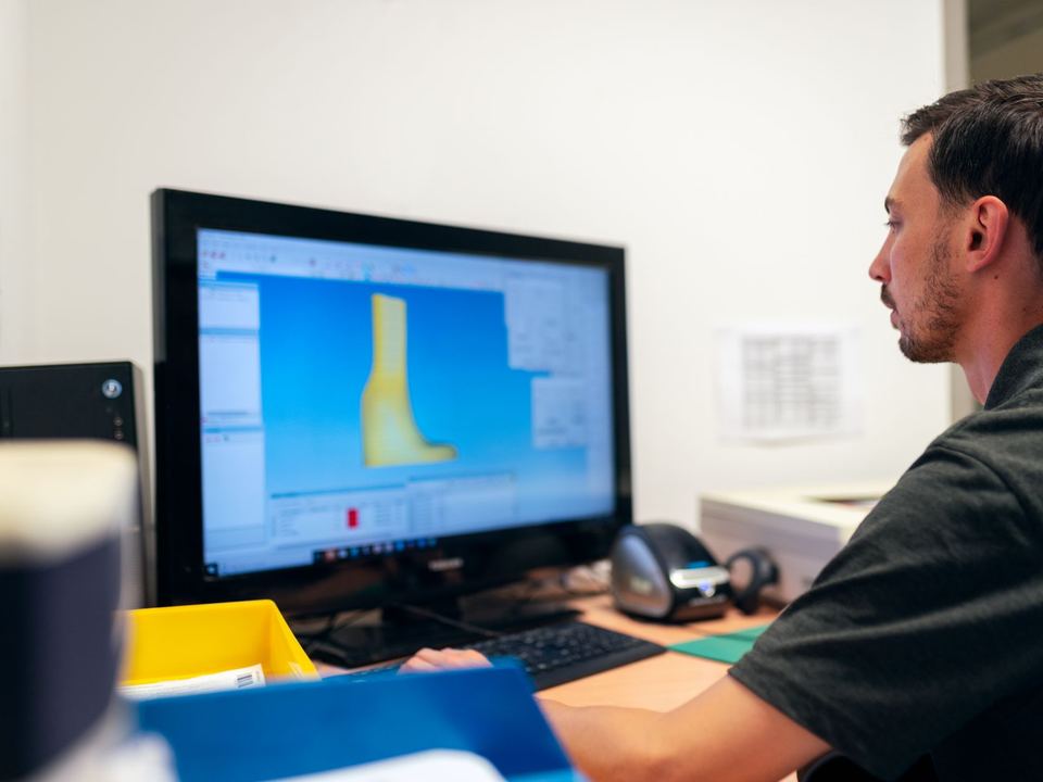 Engineer working on prosthetic design using specialized software in an office setting.