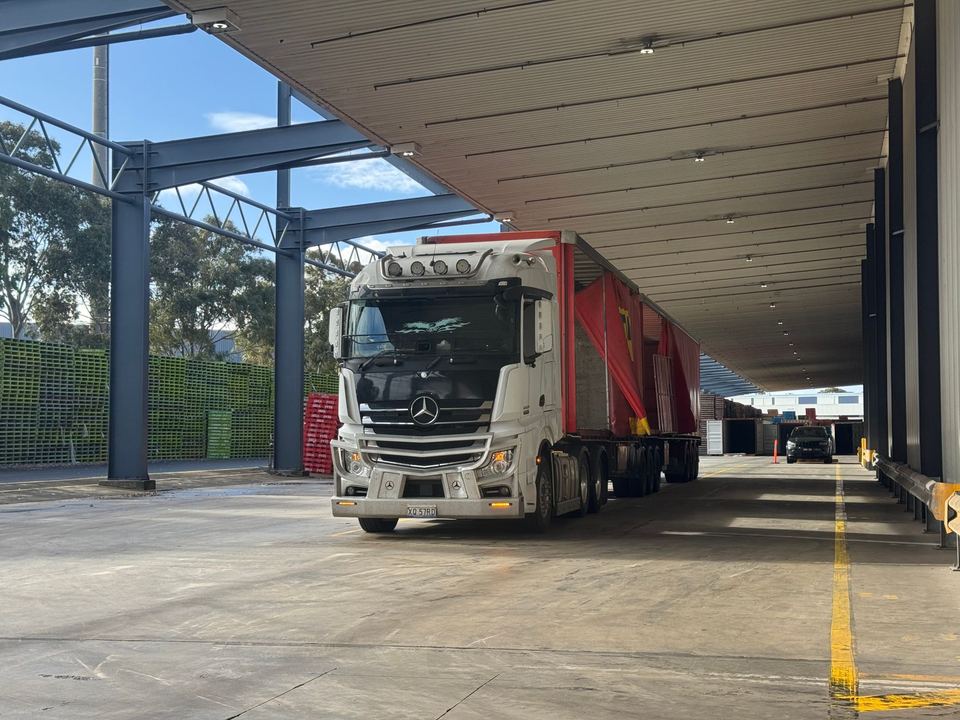 Large truck parked in a loading bay under a roof, ready for industrial transport.