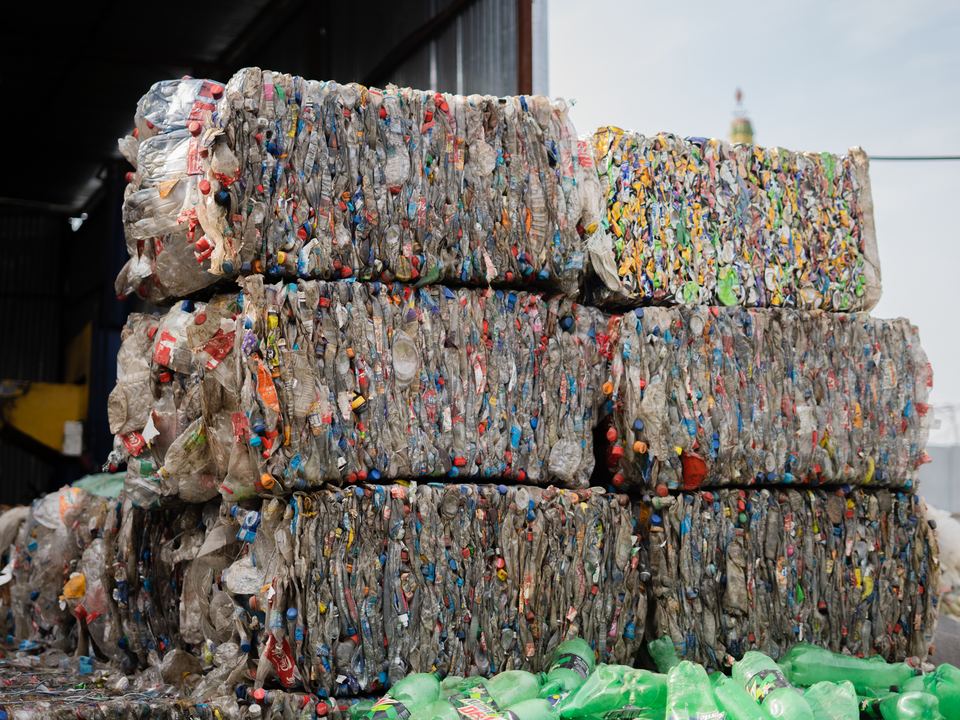 Stacked compressed plastic bottles at a recycling facility, ready for processing.