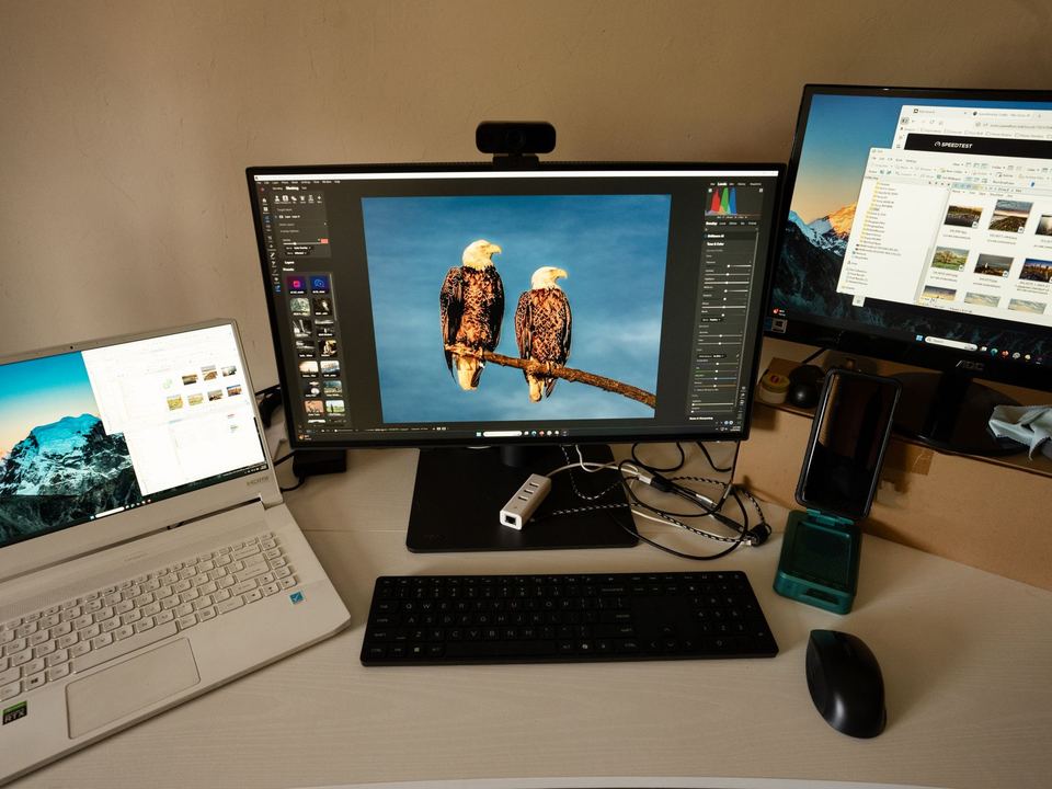 Photographer's workspace with dual monitors, laptop, and editing software.